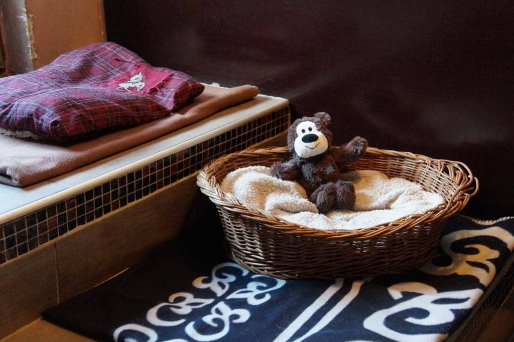 Weiches Körbchen mit Teddybär und warmen Decken im Ruheraum